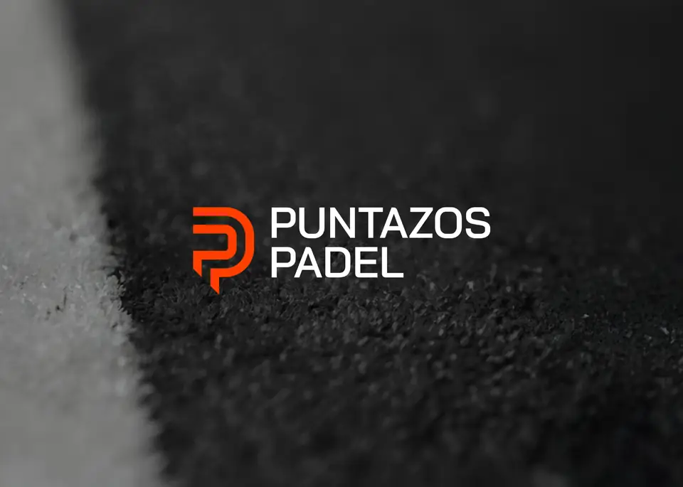 Logotipo de Puntazos Pádel en naranja y blanco sobre la superficie de una pista