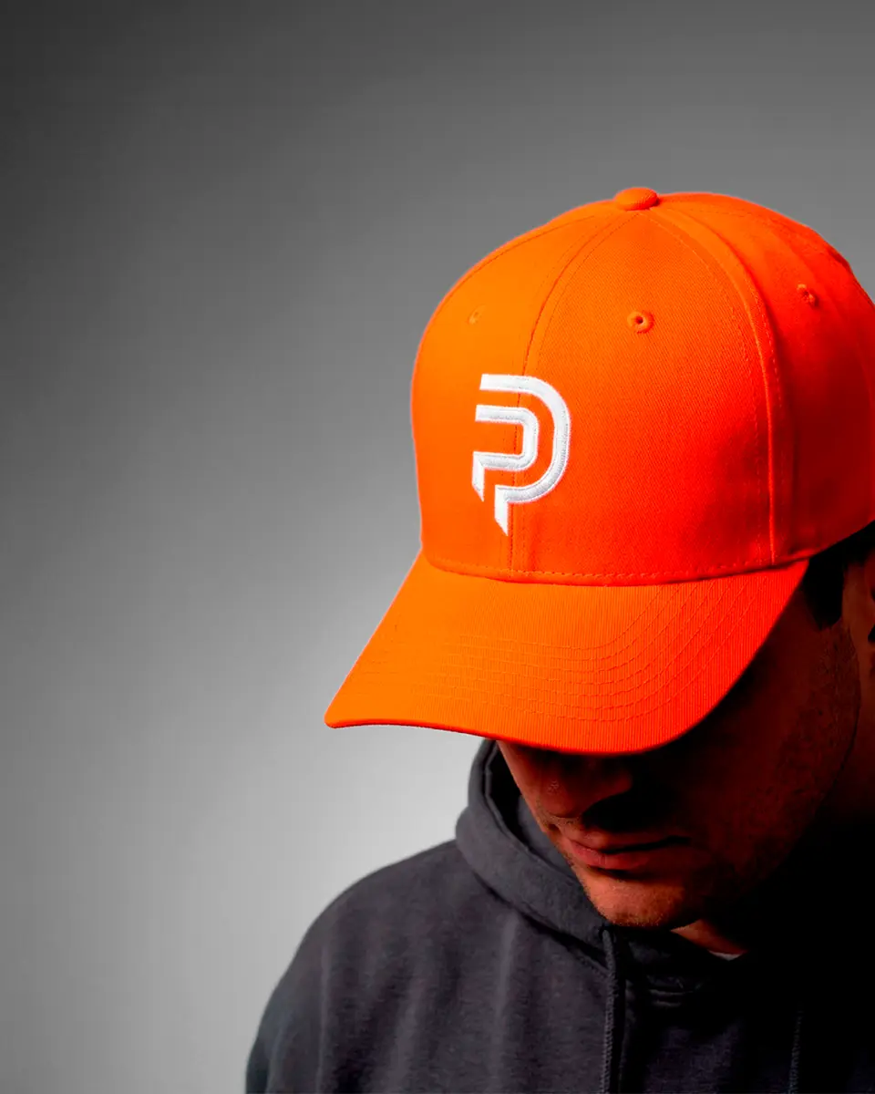 Gorra naranja con el isotipo de Puntazos Pádel bordado en blanco