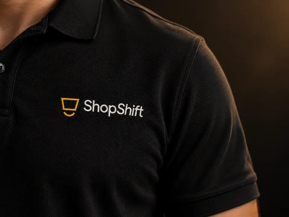 Detalle de un polo negro con el logotipo de ShopShift bordado